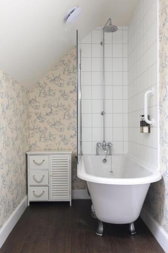 a white bath tub in a bathroom with wallpaper at Monteviot Stables West in Jedburgh