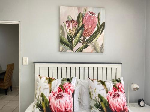 a painting above a bed with pink flowers on it at The Protea & Vine in Paarl