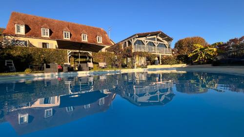 a pool of water in front of a house at Hôtel Bien-Être Aux Cyprès de Marquay in Marquay