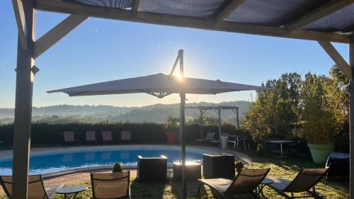 a pool with a table and a umbrella and chairs at Hôtel Bien-Être Aux Cyprès de Marquay in Marquay