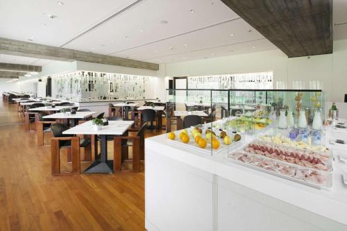 a restaurant with tables and chairs and a display of fruit at NH Milano Congress Centre in Assago