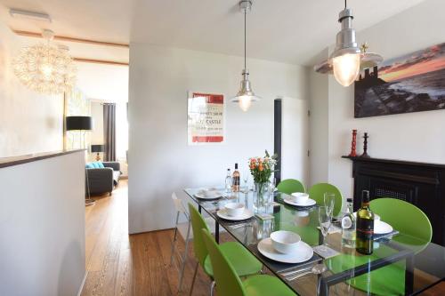 a dining room with a table and green chairs at Arthouse Canterbury-Free Secure Parking in Canterbury