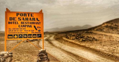 a sign on a dirt road in the desert at Porte De Sahara Ouzina in Ouzina