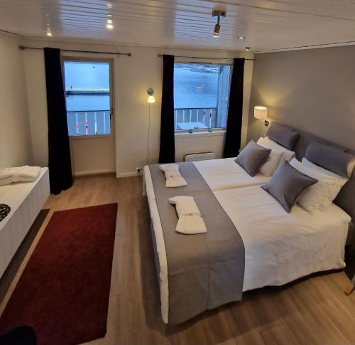 a bedroom with a large white bed with two windows at Flåm Marina in Flåm
