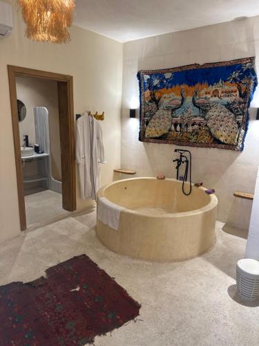 a large tub in a bathroom with a painting on the wall at Beyt Merin Konağı in Mardin
