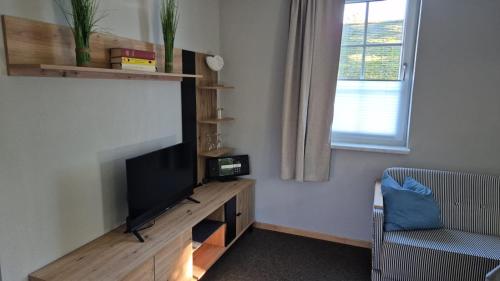 a living room with a flat screen tv and a chair at Landidyll Monte Gristow in Mesekenhagen