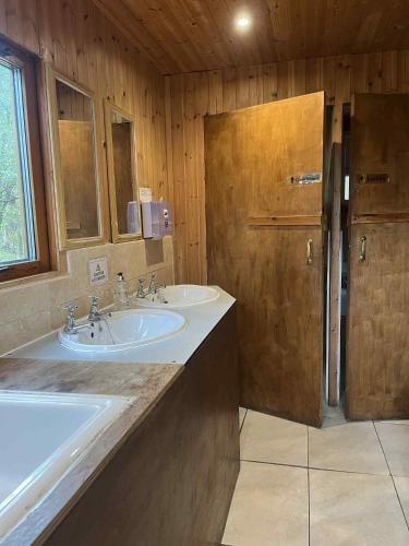 a bathroom with two sinks and a wooden wall at Pine Marten Bar Glenmore Pods in Aviemore