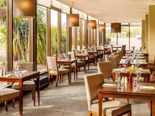a restaurant with tables and chairs and windows at Mercure Telford Centre Hotel in Telford