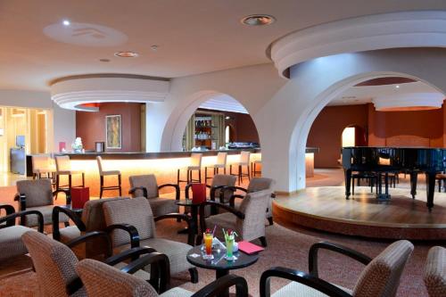 a hotel lobby with a piano and chairs at Royal Tulip Taj Sultan in Hammamet