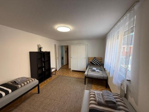 a living room with two beds and a window at ARCOS Apartment - Geräumige 3-Zimmer-Wohnung mit 8 Einzelbetten - Perfekt für Familien, Gruppen oder Monteure in Kappel-Grafenhausen