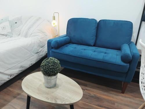 a blue couch and a table in a living room at Appartement Parking Wifi Terrasse cosy in Condé-sur-Sarthe