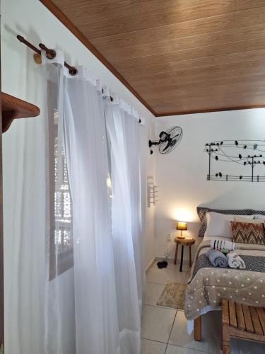a bedroom with a bed with white curtains and a window at Chalés Metanóia in São Pedro da Serra