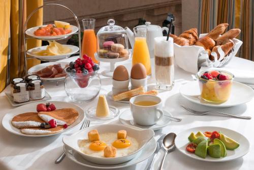a table topped with plates of breakfast foods and eggs at Hôtel Métropole Monte-Carlo - Spa Guerlain in Monte Carlo