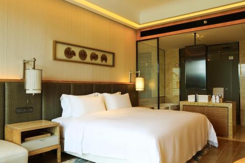 a bedroom with a large white bed and a shower at Harman Resort Hotel Sanya in Sanya