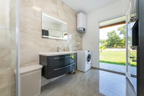 a bathroom with a sink and a washing machine at Holiday home Relax in Posedarje