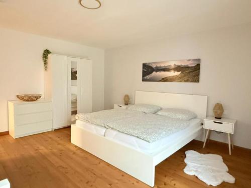 a white bedroom with a bed and a mirror at NEU! Auszeit am Hirzenkopf in Steinberg-Deckenhardt