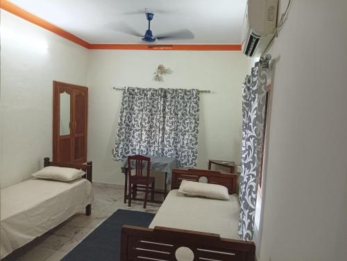 a room with two beds and a table in it at Shield Guest Accommodation in Pudunagaram