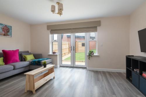 a living room with a couch and a tv at Spacious Milton Keynes Townhouse 2 Designated Parking Spaces Near Centre MK, MK Bowl, Universal Studios & Transport Links Ideal for Families & Contractors in Milton Keynes