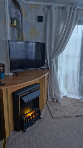 a fireplace in a living room with a television at Static Caravan situated at Wigbay, Stranraer in Stranraer