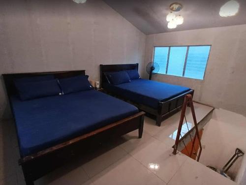 two beds in a room with blue sheets at Tsinoy Villa in Pandi