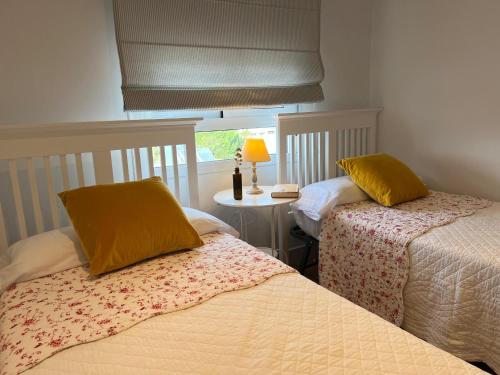 a bedroom with two beds and a table with a lamp at Casa Rural Las Candelas in San Vicente de Alcántara