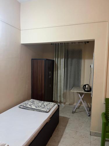 a small bedroom with a bed and a table at Hemalata Hilltop Residency Kamakhya in Guwahati