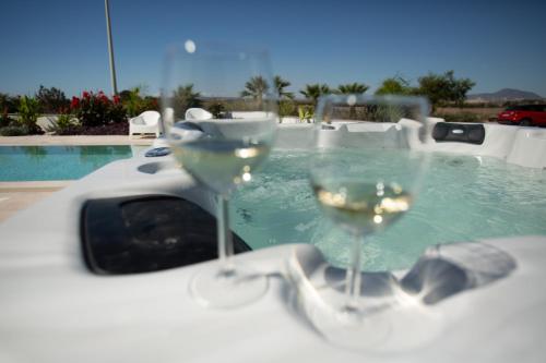 Dos copas de vino blanco sentadas en una mesa junto a una piscina en Nadine sea side villas, en Lárnaca
