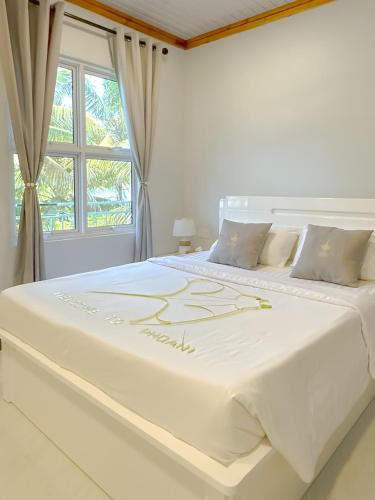 a large white bed in a room with a window at Dhoani Maldives Boutique in Kendhoo
