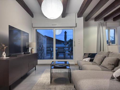 a living room with a couch and a tv at Jardin Secret - Maison 80 m2, jardin privé & parking, début Route des Vins in Marlenheim