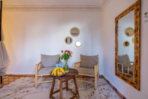 a room with a table and two chairs and a mirror at Riad des remparts Marrakech in Marrakech