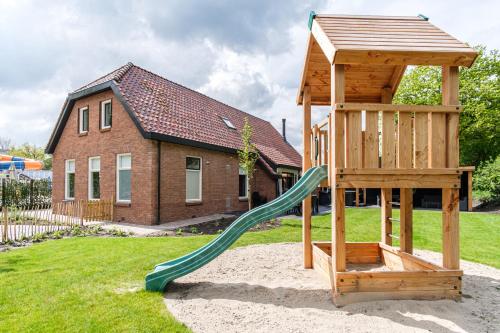 une aire de jeux en bois avec toboggan en face d'une maison dans l'établissement Kampeerdorp de Zandstuve - Kindvriendelijke Vakantiepark, à Rheeze