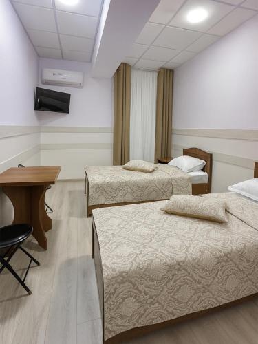 Cette chambre comprend 3 lits, une table et un bureau. dans l'établissement Hotel Sofia Samarkand, à Samarcande