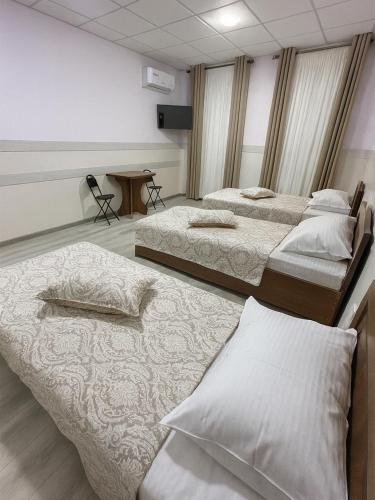 une chambre avec trois lits et une table dans l'établissement Hotel Sofia Samarkand, à Samarcande