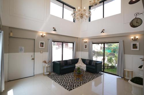 a living room with a couch and a chandelier at EKO STAY Gold - Gatsby Villa in Lonavala