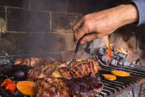 a person cooking meat on a grill with a spatula at El Descanso de la Furia in San Carlos