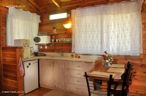 une cuisine avec un évier et une table dans une cabine dans l'établissement בקתות הר ארבל, à Arbel