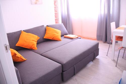 un sofá gris con almohadas naranjas en la sala de estar en Apartamento Orange Triana centro, en Sevilla