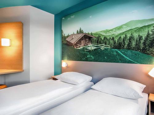 two beds in a room with a painting of a house at B&B Hotel München-Putzbrunn in Putzbrunn