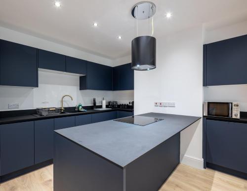 a kitchen with blue cabinets and a counter top at Kinsale House by Cliftonvalley Apartments in Brislington