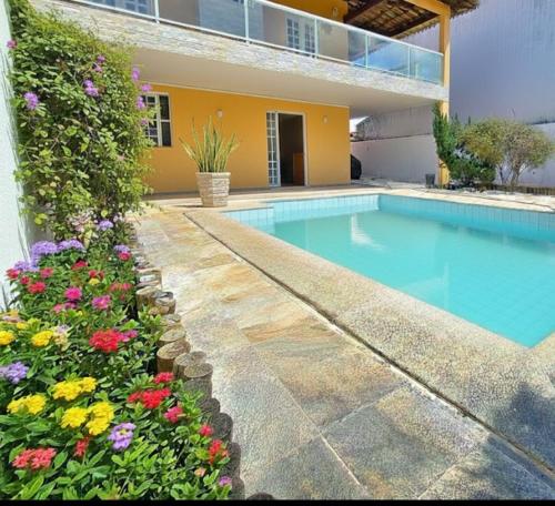 a swimming pool in front of a house with flowers at Quarto compartilhado 8 leitos Valor por pessoa in Aracaju