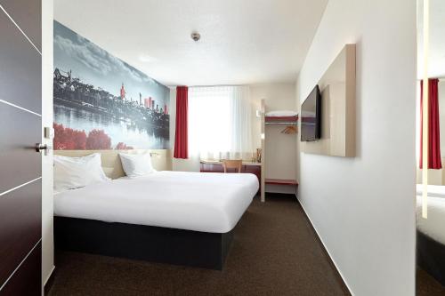 a hotel room with a white bed and a tv at B&B Hotel Warszawa-Okęcie in Warsaw