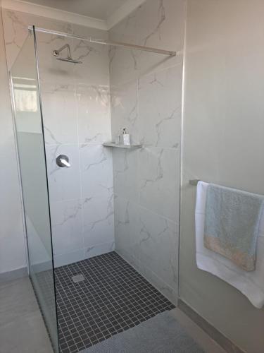 a shower with a glass door and a towel at Hadeda Cottage in Johannesburg