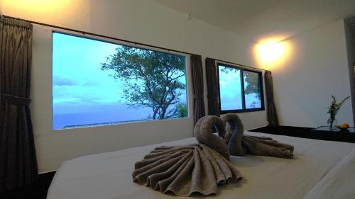 a bedroom with two towels on a bed with two windows at Nunggalan Octopus 2 in Uluwatu