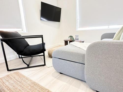 a living room with a chair next to a bed at CBD Studio - Sleeps 4 - Rooftop Courtyard - Views in Wollongong