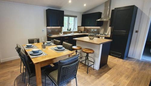 een keuken met een houten tafel en een keuken met zwarte kasten bij High Spy Luxury Lodge in Keswick