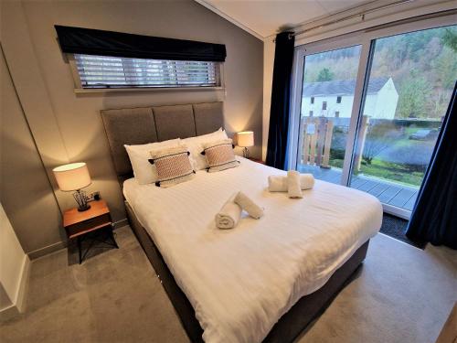een slaapkamer met een groot bed met twee schoenen erop bij High Spy Luxury Lodge in Keswick