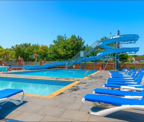 a swimming pool with blue chairs and a slide at Lady's Mile in Dawlish Warren