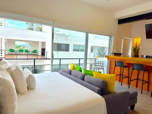 a bedroom with a large white bed and a couch at Papaya Condo Acapulco Diamante -Solo Adultos in Acapulco