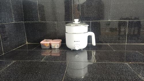 a white blender sitting on a tiled wall at THEERTHAMKARA Staycation in Nīleshwar