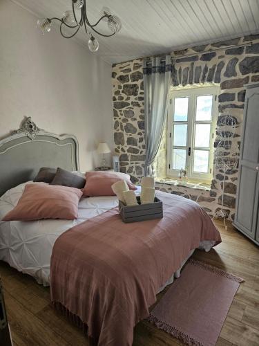 a bedroom with a large bed with a stone wall at Gîte de caractère tout confort "Au Clos des Ammonites chez Ange&Sébastien " in Labeaume